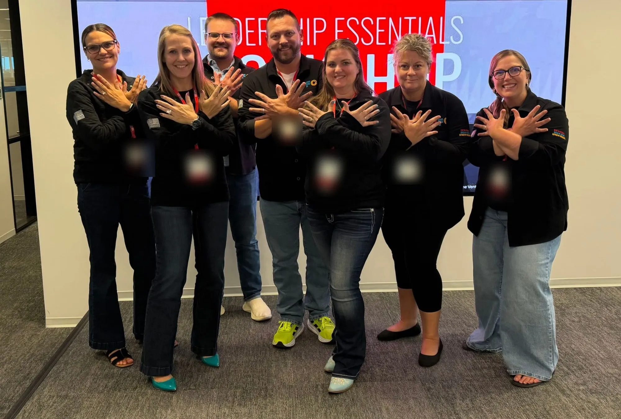Seven VFO team members in matching black VFO jackets at a leadership development workshop.